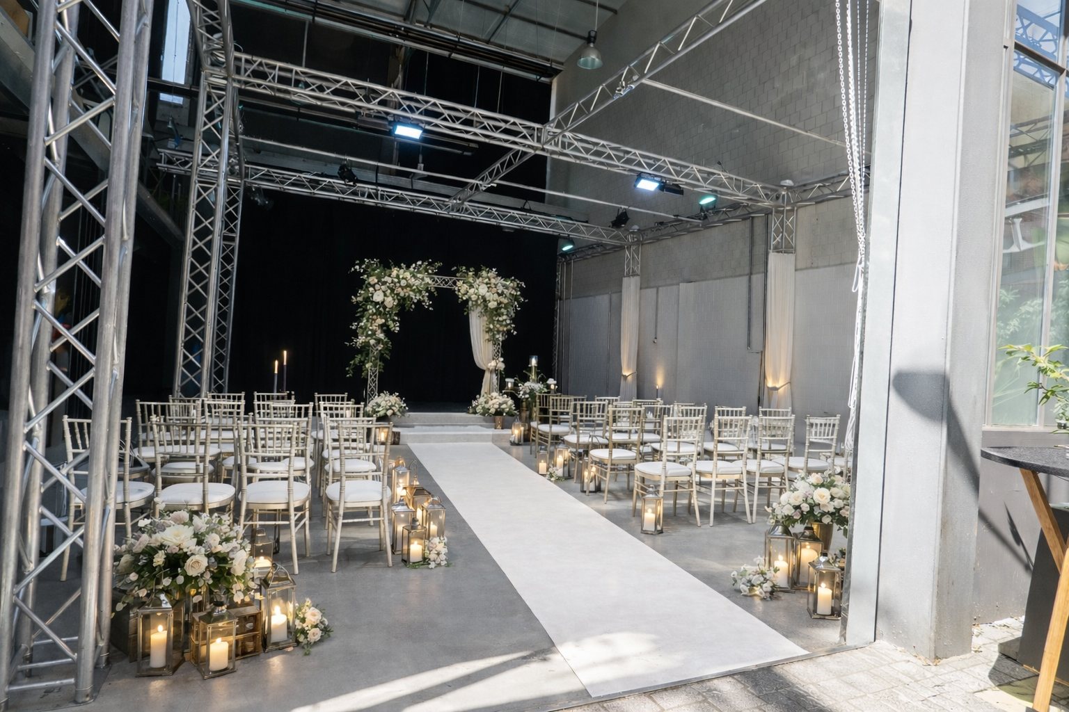 Freie Trauung mit Blumenbogen, Kerzen und weißem Läufer unter Traversen