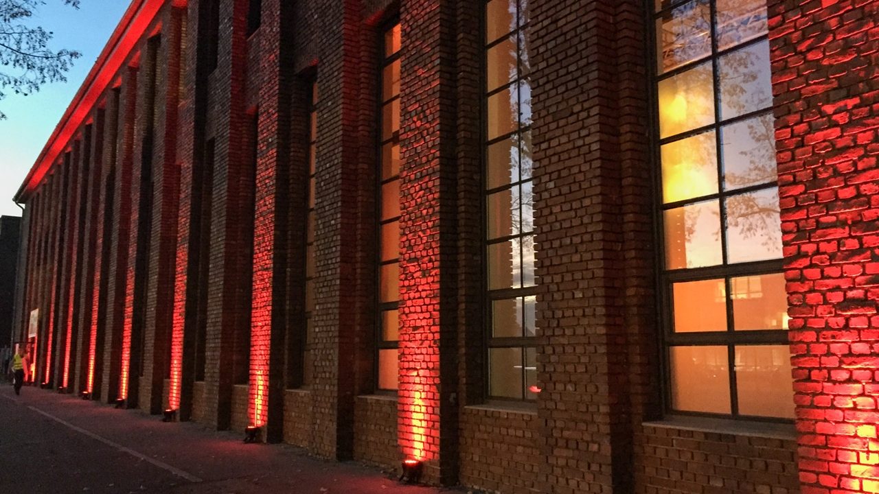 Backsteinfassade des Bauwerk bei Nacht in rotes Licht getaucht