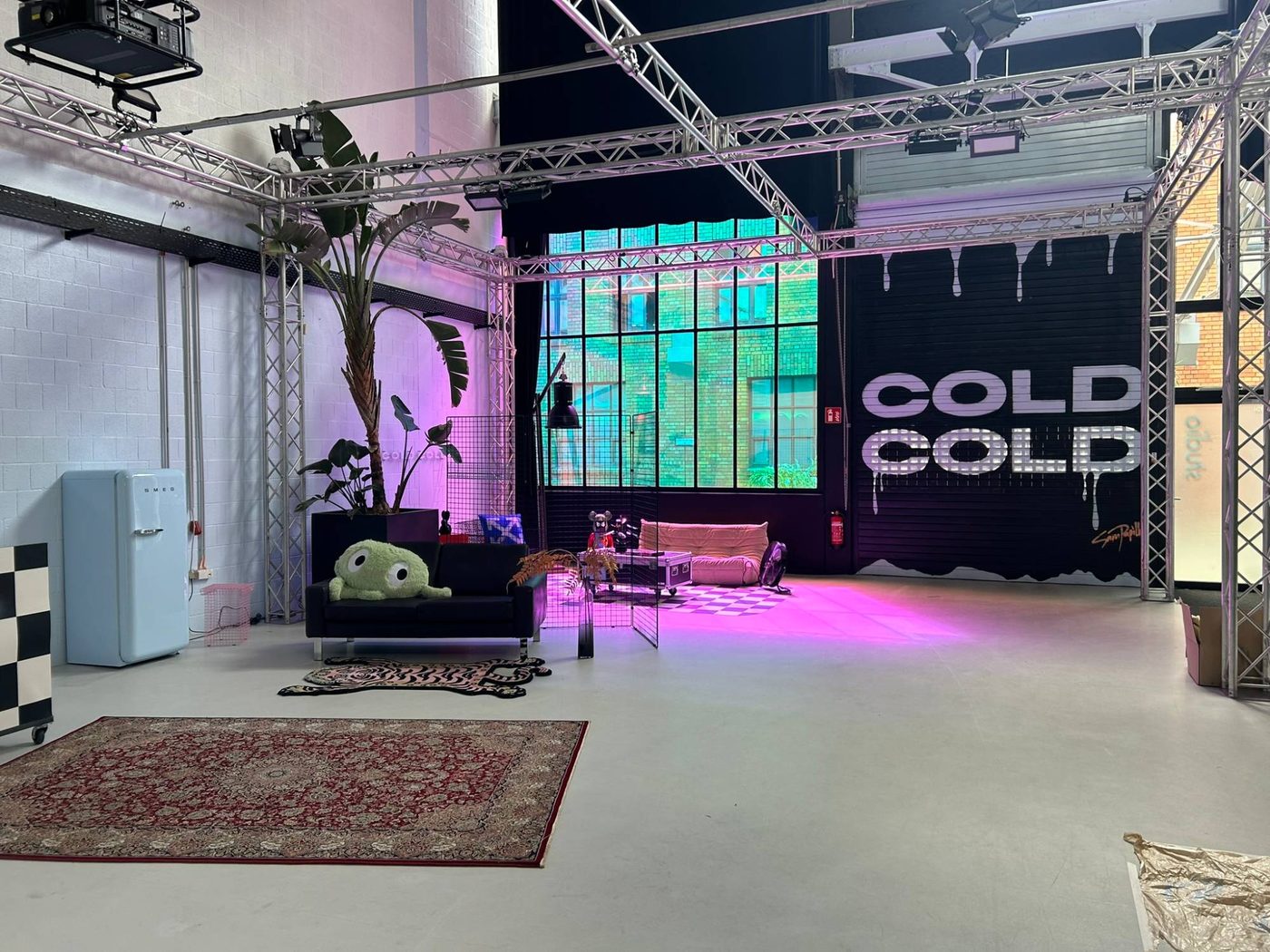 Lounge area in the studio bathed in pink and turquoise light