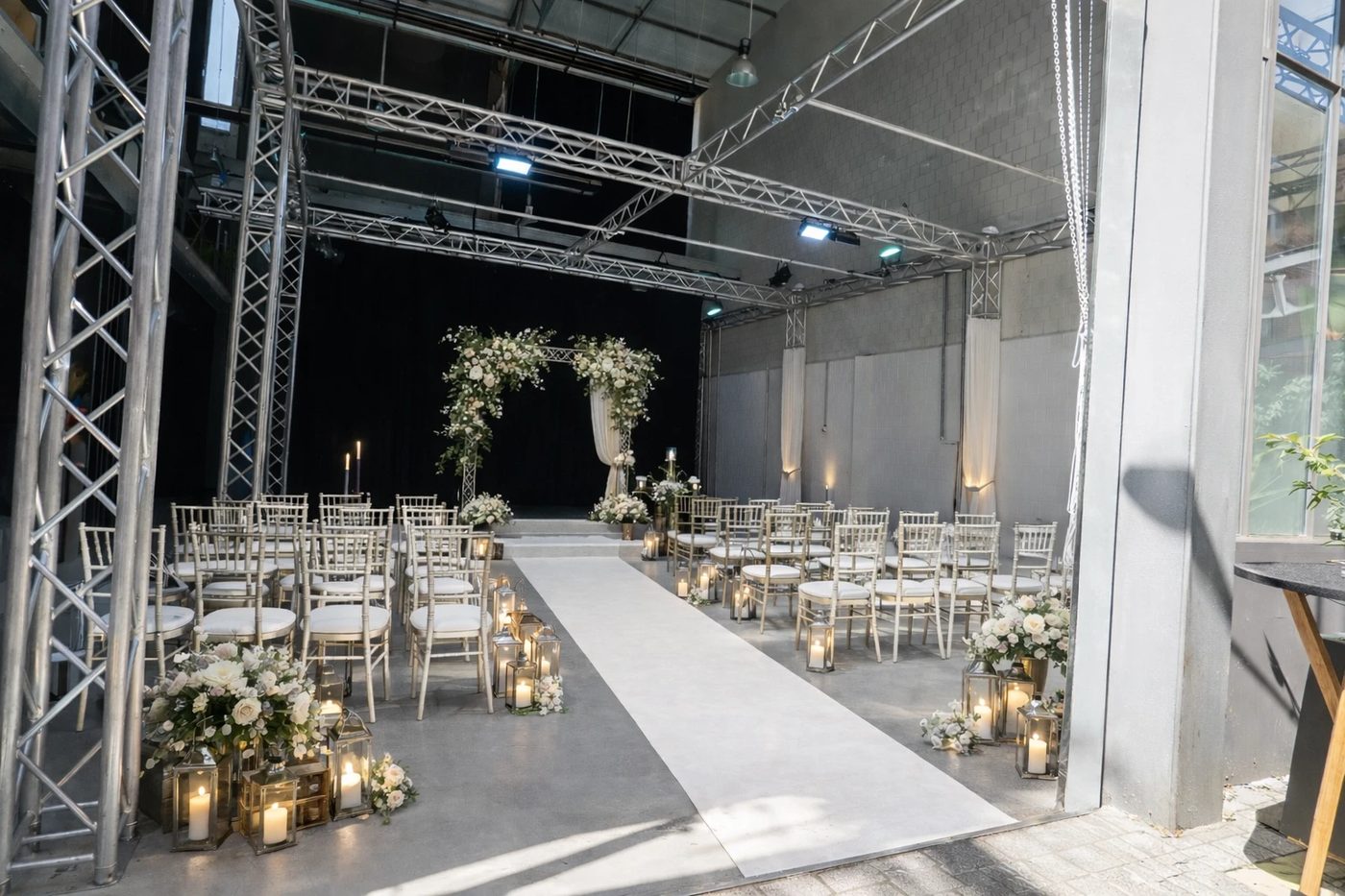 Wedding ceremony in the studio with a flower arch, candles and a white runner